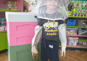 Chłopiec ubrany na granatowo w stroju pszczelarza